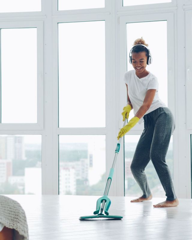 A professional cleaner mopping the floor of a bright, sunlit home