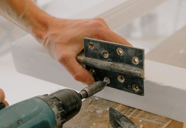 A handyman fastening a hinge fitting during interior repair work