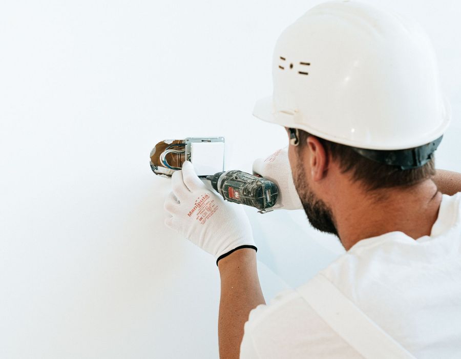 A technician fitting an electrical switch on an interior wall