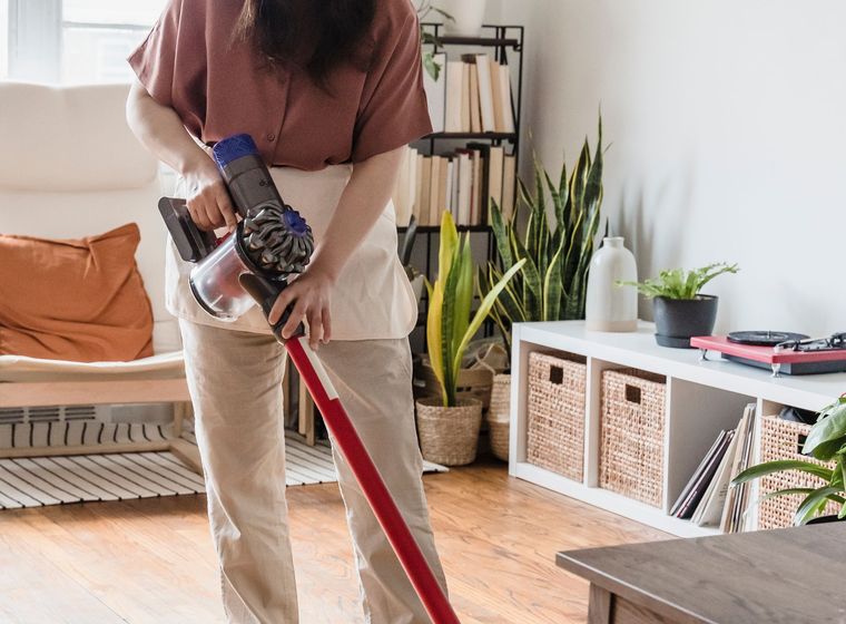A cleaner vacuuming the carpet of a bright, tidy living room in a Bahrain home