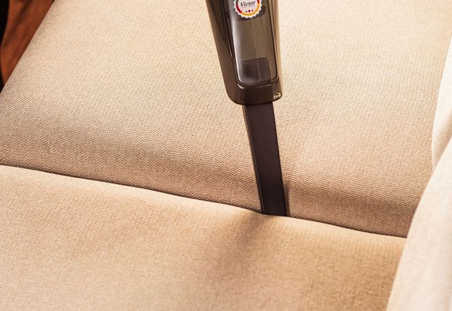 A cleaner refreshing a fabric sofa with a handheld vacuum