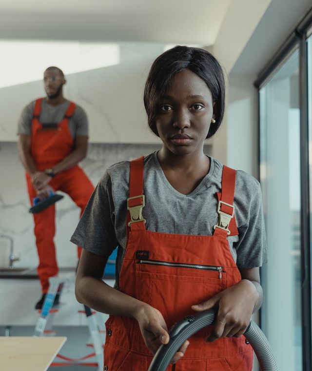 A cheerful professional cleaner carrying a vacuum hose through a bright home